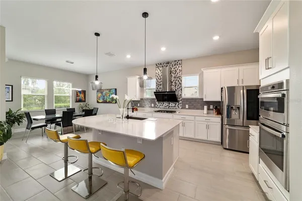a large kitchen with a table chairs refrigerator and chairs