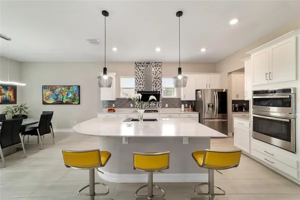 a kitchen with stainless steel appliances granite countertop a kitchen island a stove a microwave oven a dining table and chairs