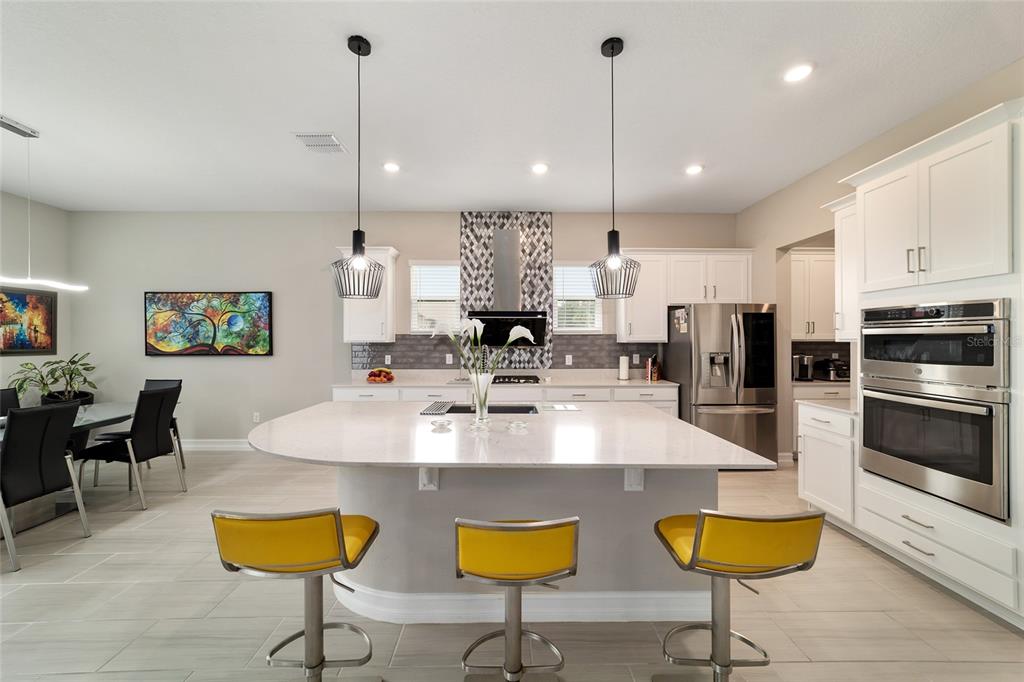 906 Southeast 41st Street Ocala, FL 34480 - Photo 8 of 37 a kitchen with stainless steel appliances granite countertop a kitchen island a stove a microwave oven a dining table and chairs