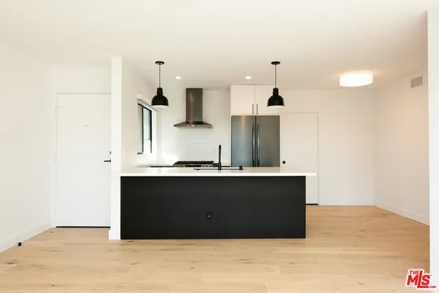 a kitchen with kitchen island sink and refrigerator