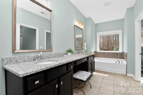 a bathroom with a granite countertop bathtub sink vanity and mirror