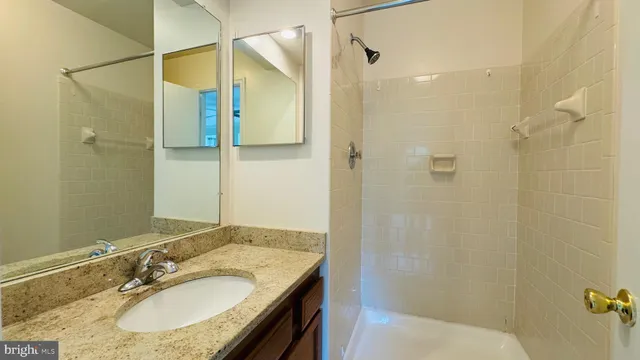 a bathroom with a granite countertop shower sink and mirror