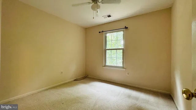 an empty room with a window and a ceiling fan