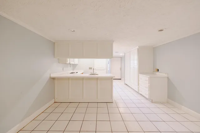 a kitchen with a sink a refrigerator and white cabinets
