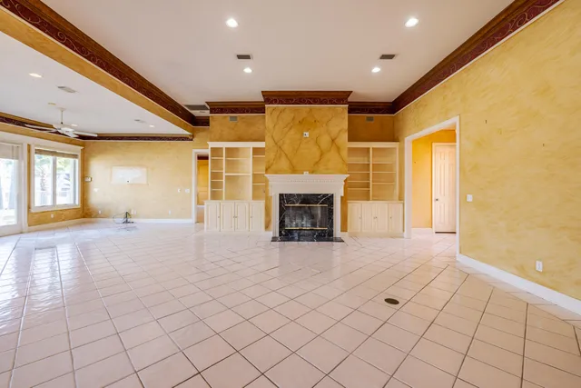 an empty room with windows and fireplace