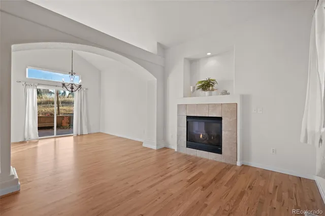 a view of an empty room with wooden floor fireplace and a window