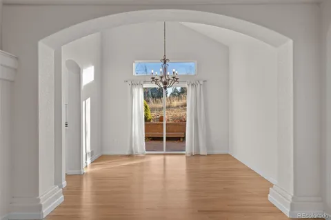 a view of an empty room with window and wooden floor