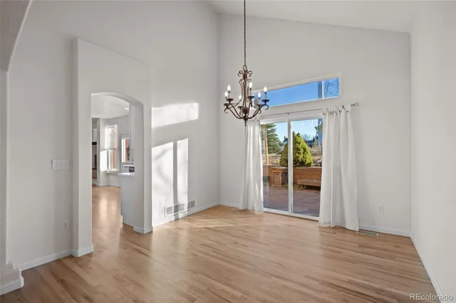 a view of a room with wooden floor chandeliers and kitchen view