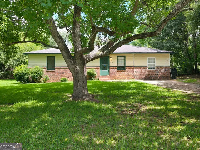 a front view of a house with a yard and trees
