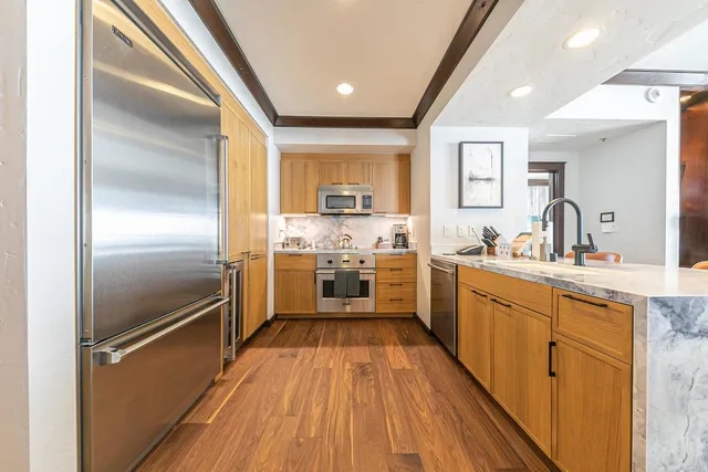 a kitchen with stainless steel appliances a sink cabinets and a wooden floor