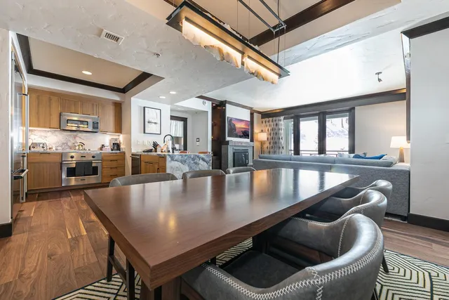 a kitchen with stainless steel appliances granite countertop a stove a sink a refrigerator dining table and chairs