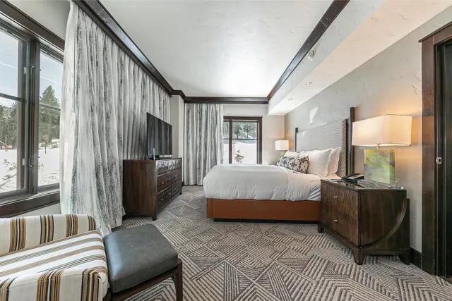 a bedroom with a bed wooden floor and a large window