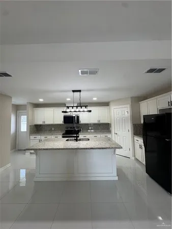 a large kitchen with stainless steel appliances kitchen island a stove a refrigerator a oven and a sink with granite countertops