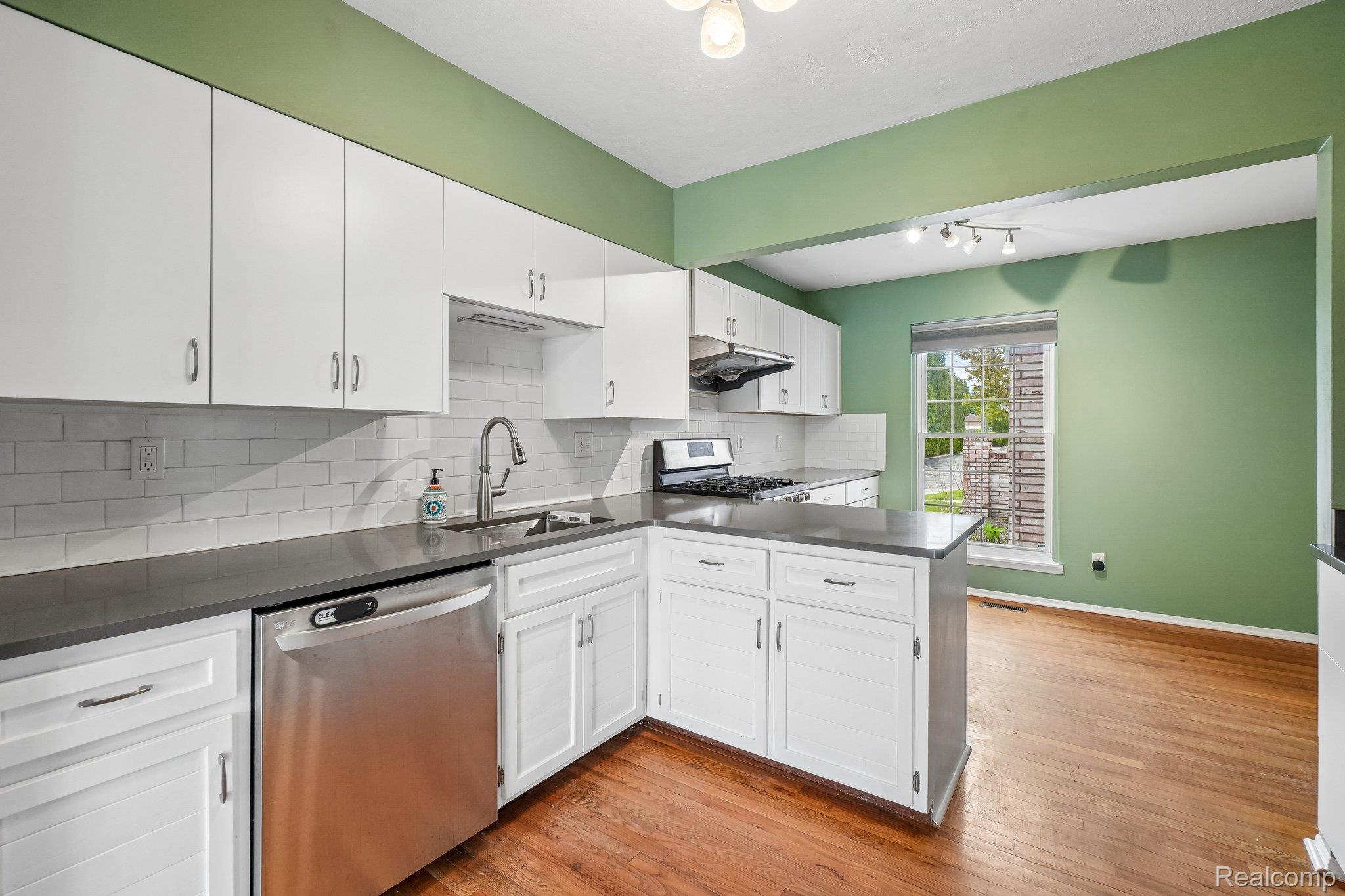 44 Stratford Lane Rochester, MI 48309 - Photo 11 of 37 Kitchen with white cabinetry, stainless steel appliances, decorative backsplash, and light wood-type flooring