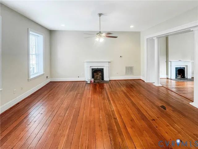 a view of empty room with wooden floor fireplace and window
