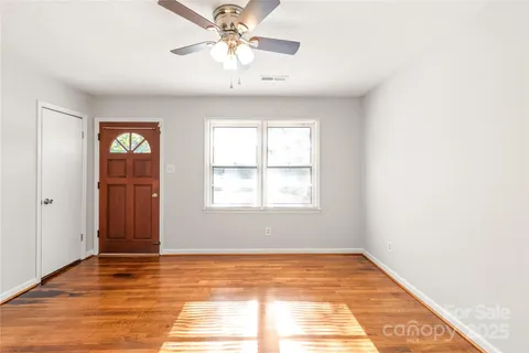 a view of an empty room with wooden floor and a window