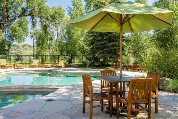 a view of swimming pool with a table and chairs under an umbrella