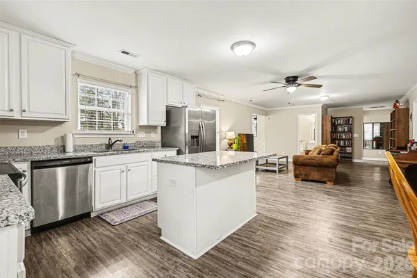 a kitchen with stainless steel appliances white cabinets a sink a stove a refrigerator and white cabinets