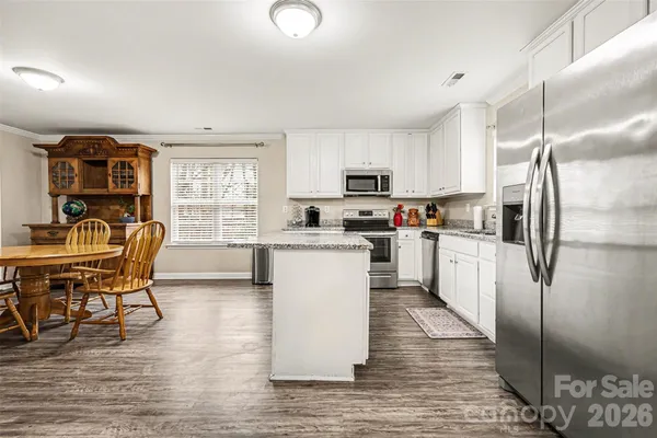 a kitchen with kitchen island a refrigerator table and chairs
