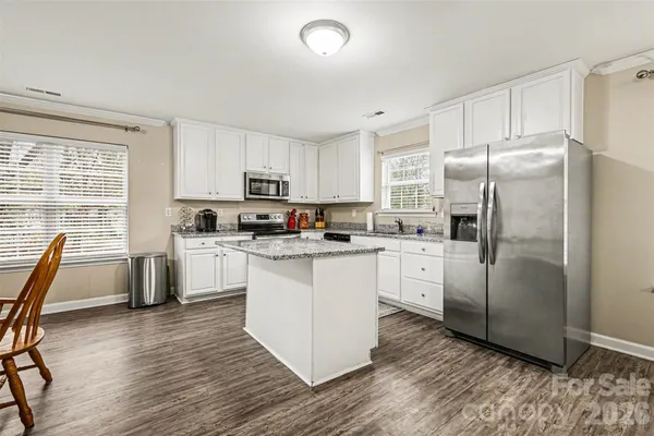 a kitchen with white cabinets stainless steel appliances a sink and a window