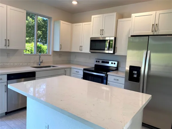 a kitchen with stainless steel appliances a microwave sink refrigerator and cabinets