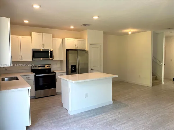 a kitchen with kitchen island a refrigerator stove and microwave