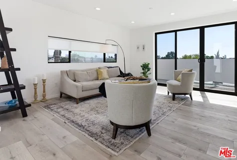 a living room with furniture a large window and wooden floor