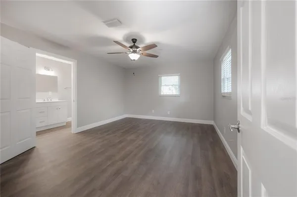 an empty room with wooden floor fan and windows