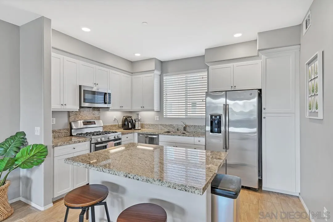 2840 Athens Road, Unit 10 Chula Vista, CA 91915 - Photo 3 of 35 a kitchen with stainless steel appliances granite countertop a refrigerator a stove a sink a dining table and chairs with wooden floor