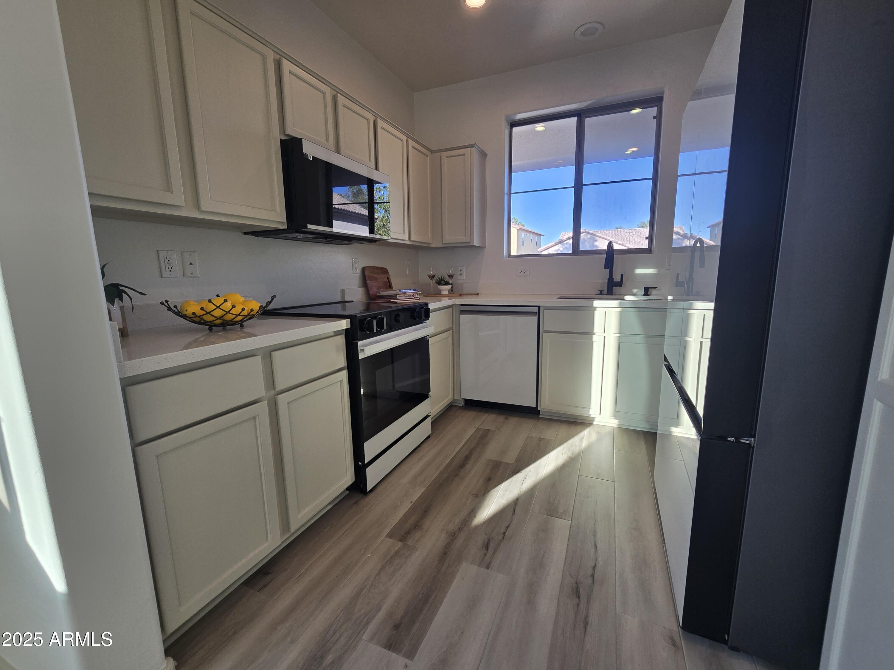18196 Calacera Street Maricopa, AZ 85138 - Photo 9 of 21 a kitchen with stainless steel appliances a stove a sink and a refrigerator