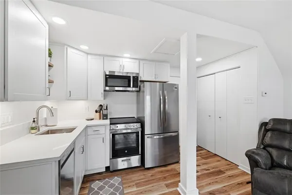 a kitchen that has a refrigerator a sink and white cabinets