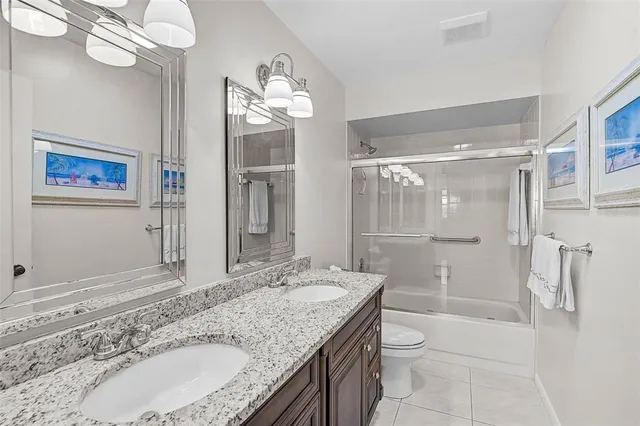 a bathroom with a granite countertop sink a toilet a mirror and shower