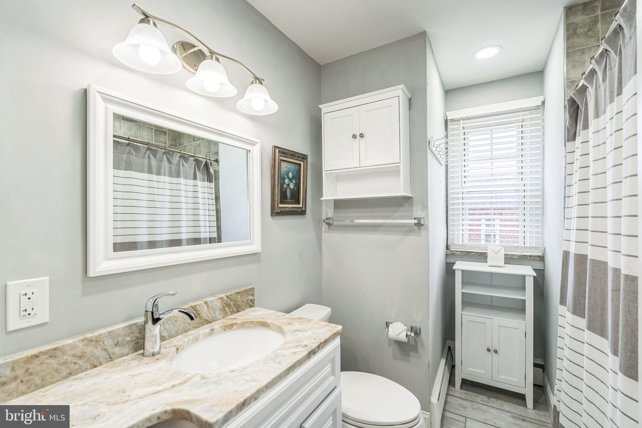 855 Medway Road Philadelphia, PA 19115 - Photo 15 of 30 a bathroom with a granite countertop sink toilet a large mirror and a window