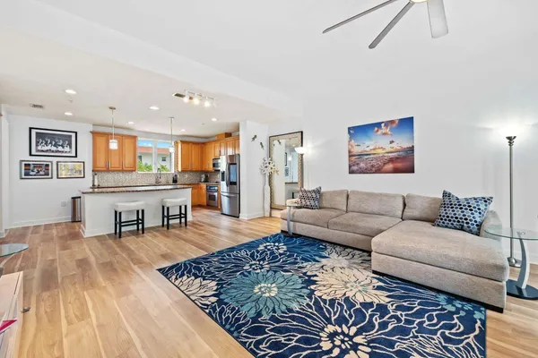 a living room with furniture and a dining table with wooden floor