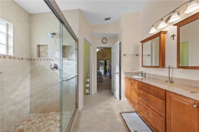 a spacious bathroom with a double vanity sink a large mirror and a shower