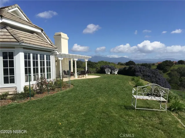 a garden with a bench in front of the house