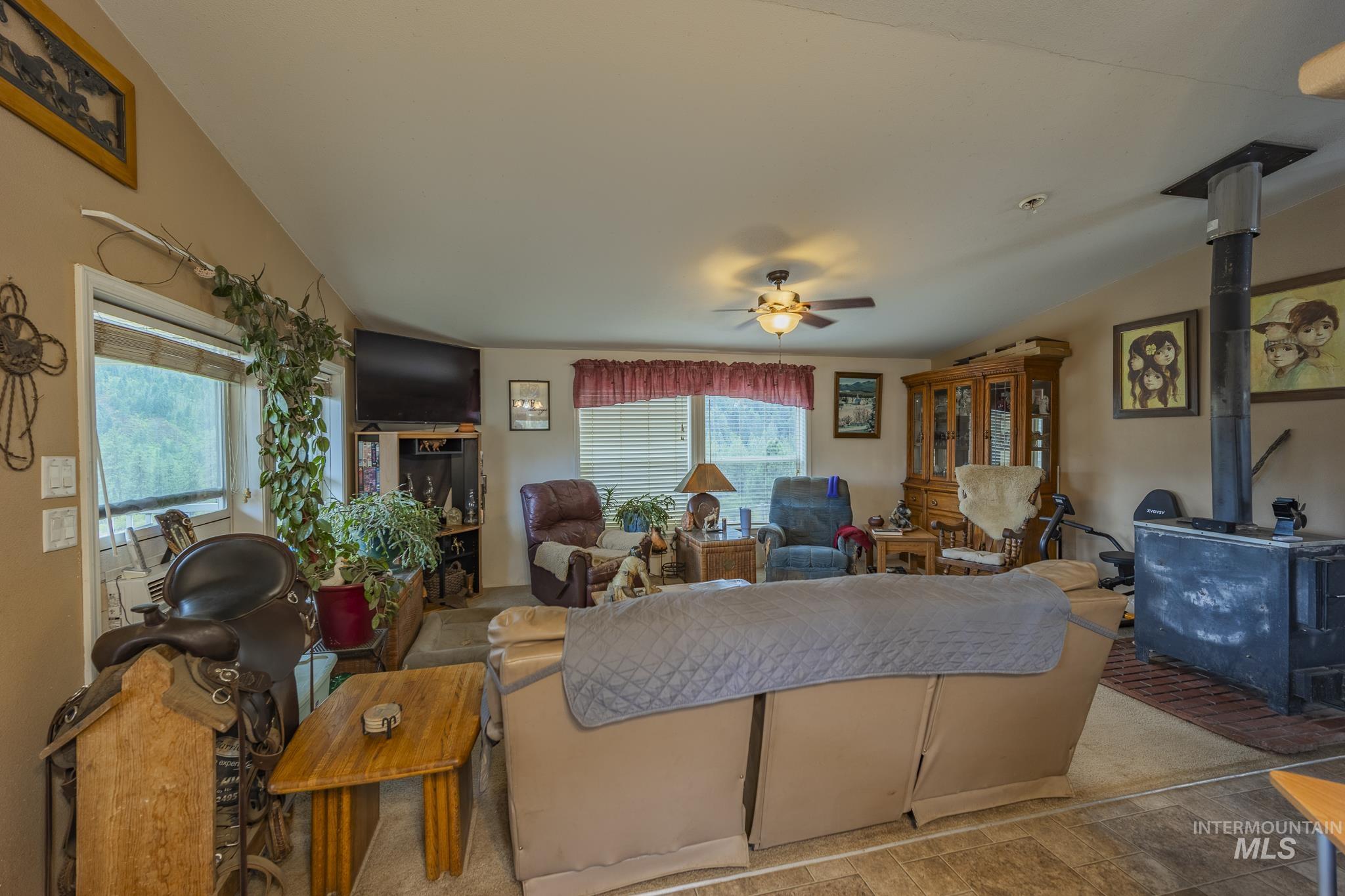 3608 Highway 13 Stites, ID 83552 - Photo 18 of 44 Living area featuring a wood stove, ceiling fan, and stone finish flooring