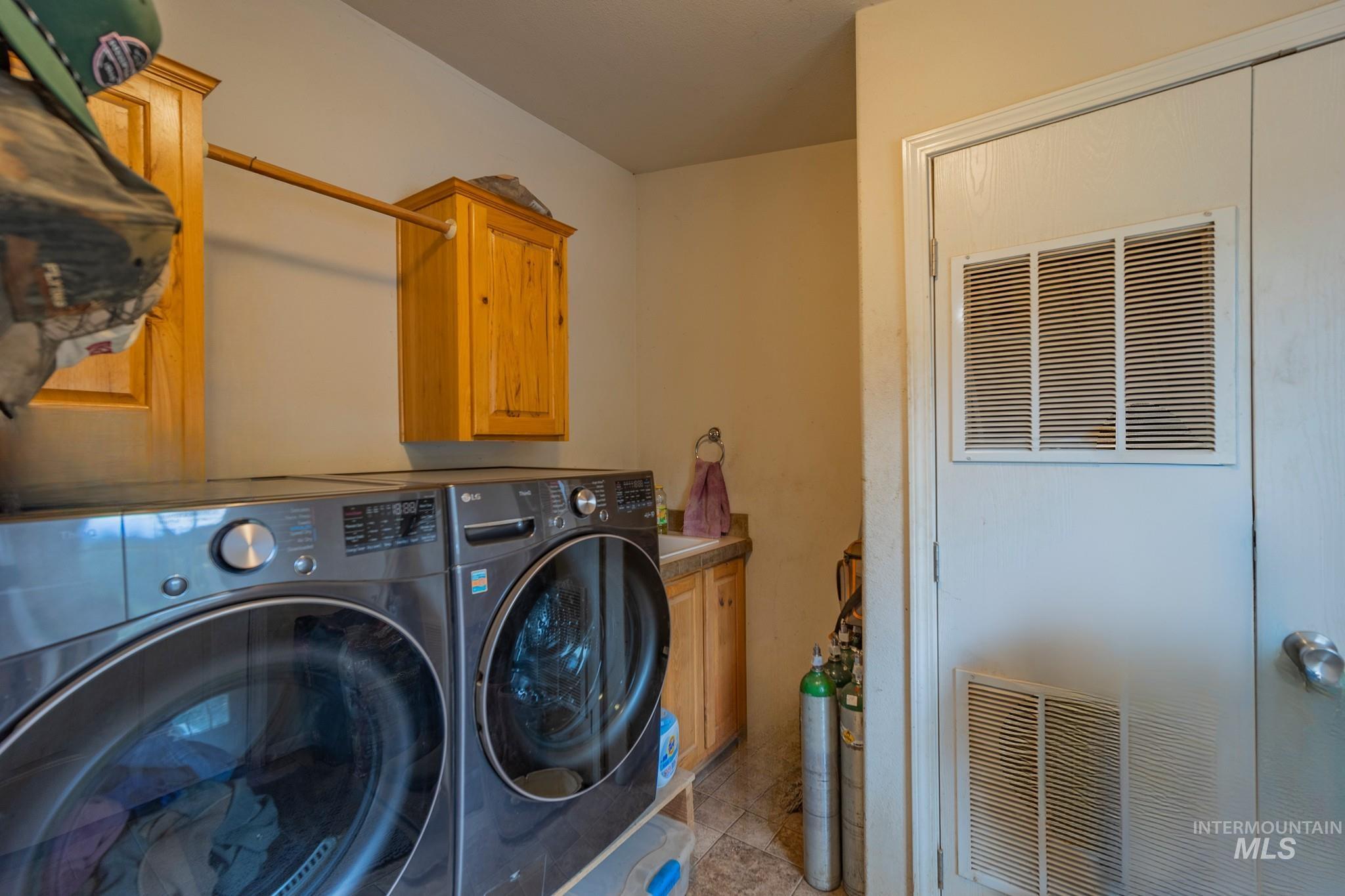 3608 Highway 13 Stites, ID 83552 - Photo 27 of 44 Washroom featuring washing machine and clothes dryer, cabinet space, and a heating unit