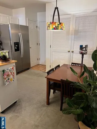 a room with a table chairs and refrigerator
