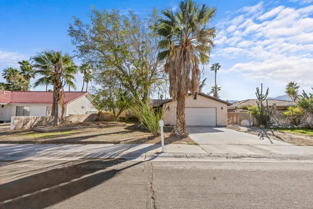 a view of a house with a cars park side of a road