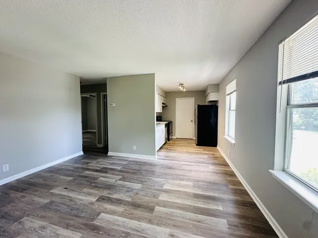 a view of an empty room with wooden floor and a window