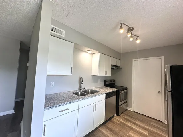 a kitchen with stainless steel appliances granite countertop a sink a stove and refrigerator