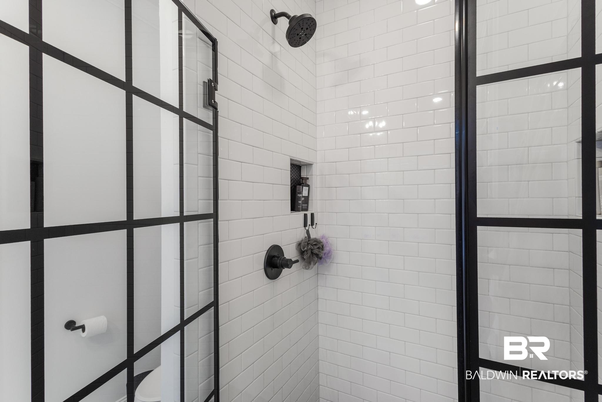 83 Caisson Trace Daphne, AL 36527 - Photo 40 of 63 Shower enclosure with black-framed glass partition, white subway tile surround, built-in shower niche, and matte black shower fixtures