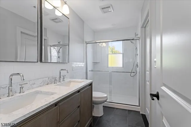 a bathroom with a double vanity sink toilet and shower