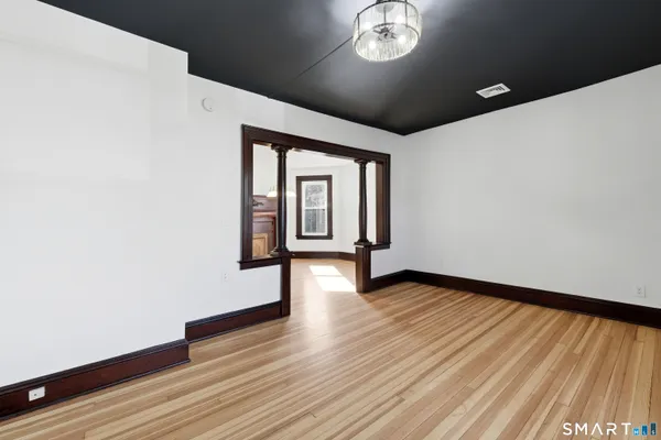 a view of an empty room with a window and wooden floor