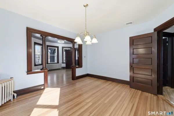 a view of a hallway with wooden floor and a chandelier