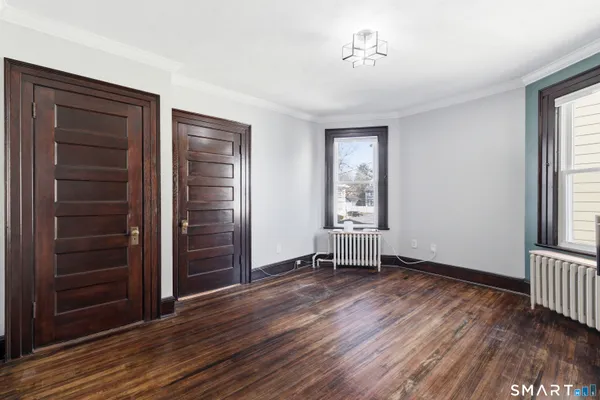 an empty room with wooden floor closet and windows