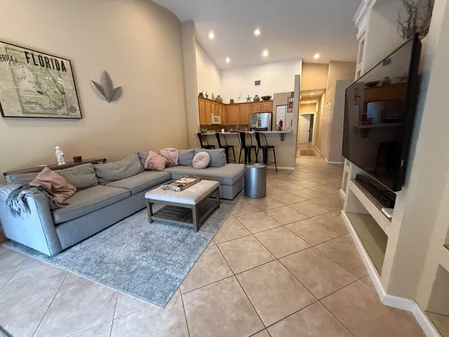 a living room with couches and kitchen view with wooden floor