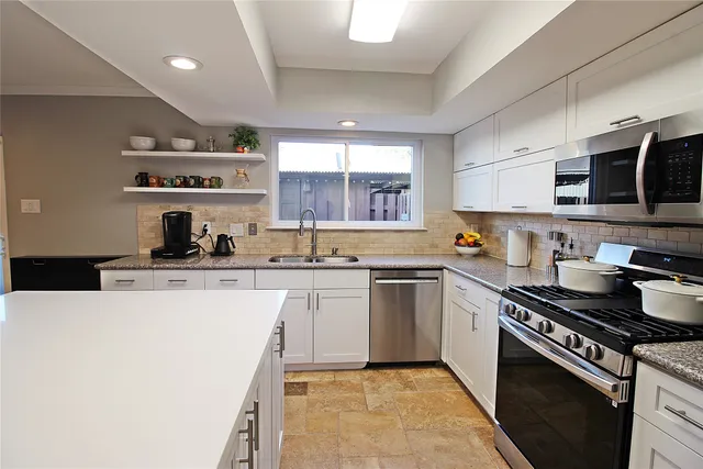a kitchen with stainless steel appliances a sink stove and cabinets