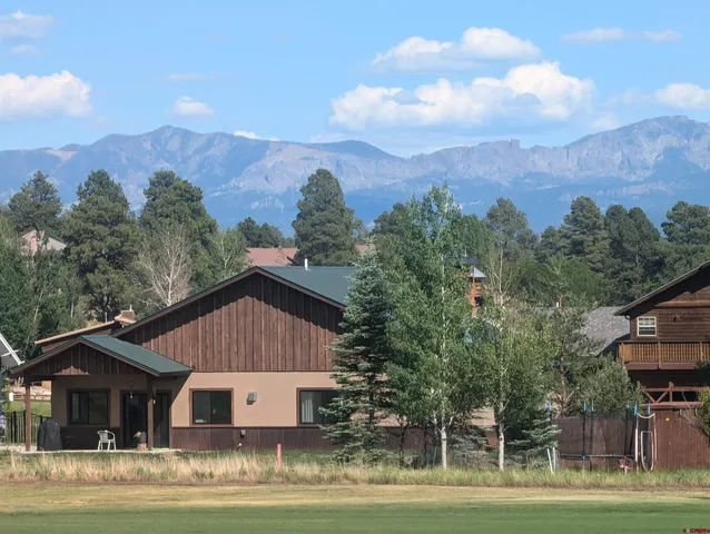 a view of a big house with a big yard and large trees